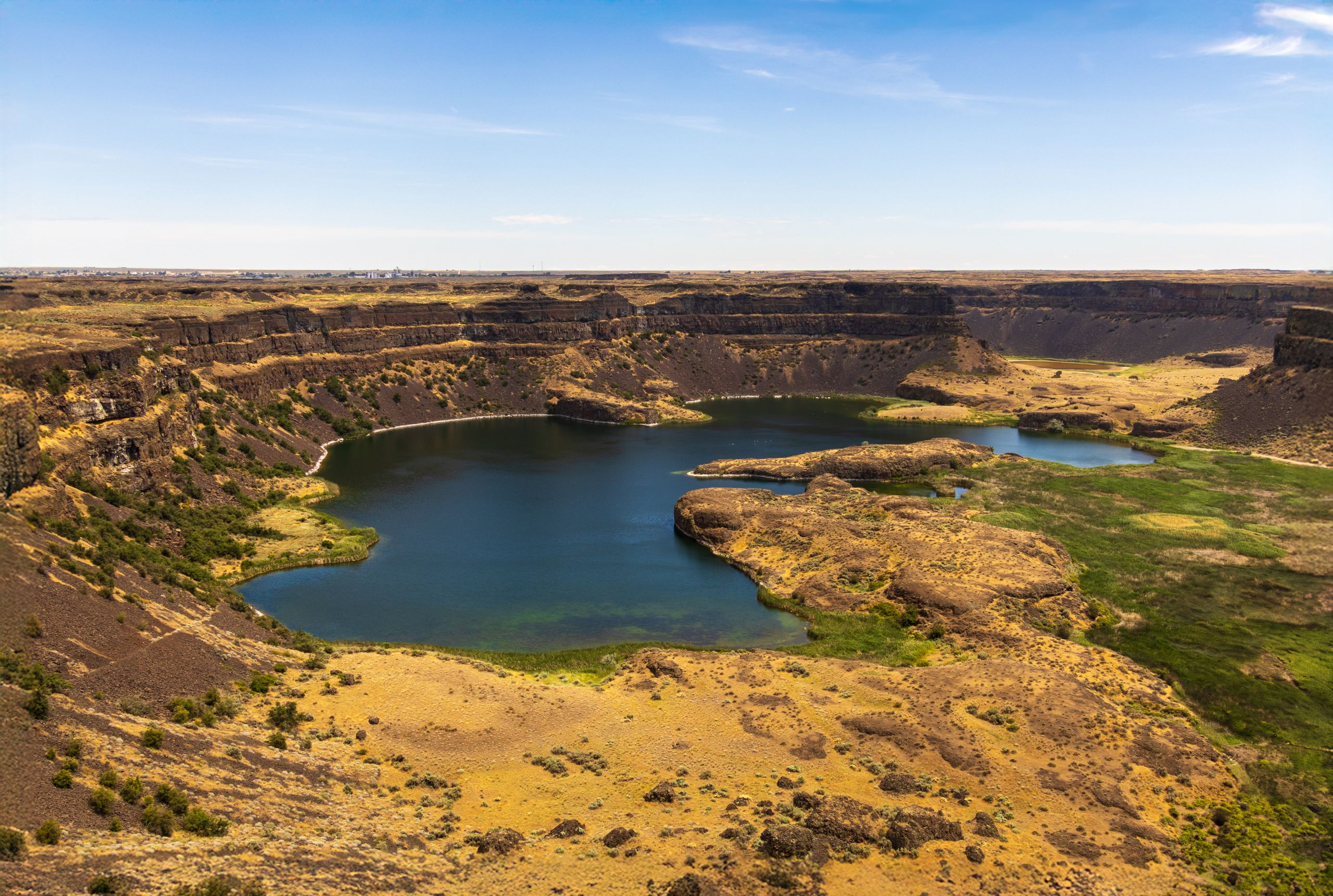 Stunning aerial photo of Dry Falls Canyon in Washington, showcasing rugged cliffs and serene water.